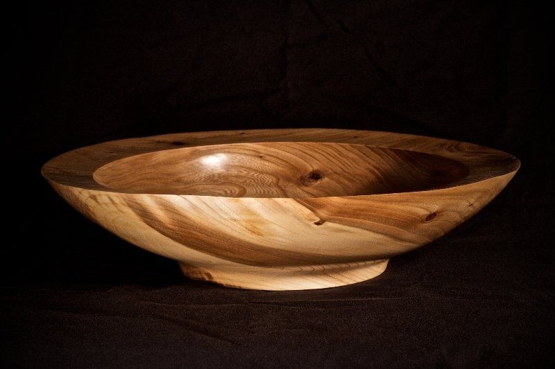 A wooden bowl is sitting on a black table.