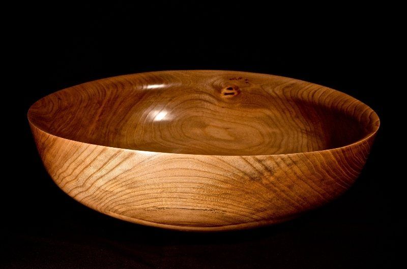 A wooden bowl is sitting on a black surface.