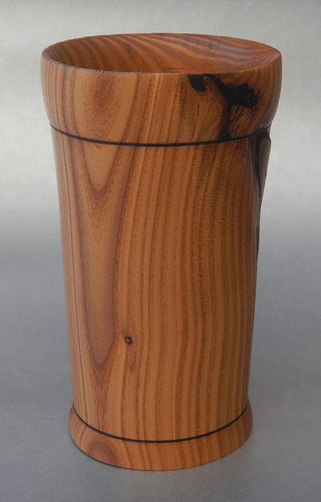 A wooden cup is sitting on a gray surface.