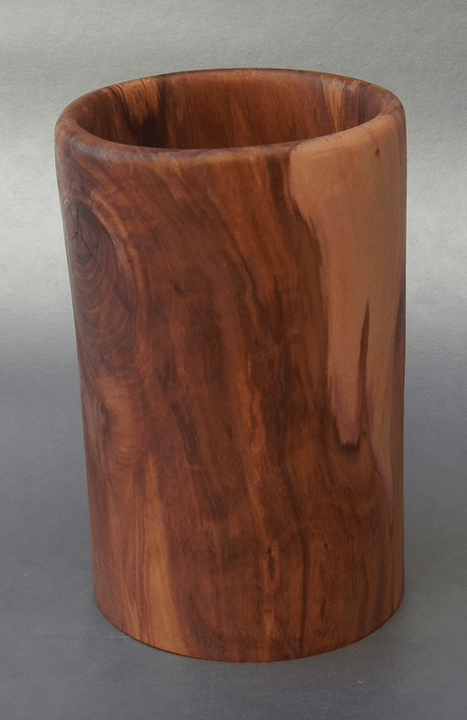 A wooden cup is sitting on a gray surface.