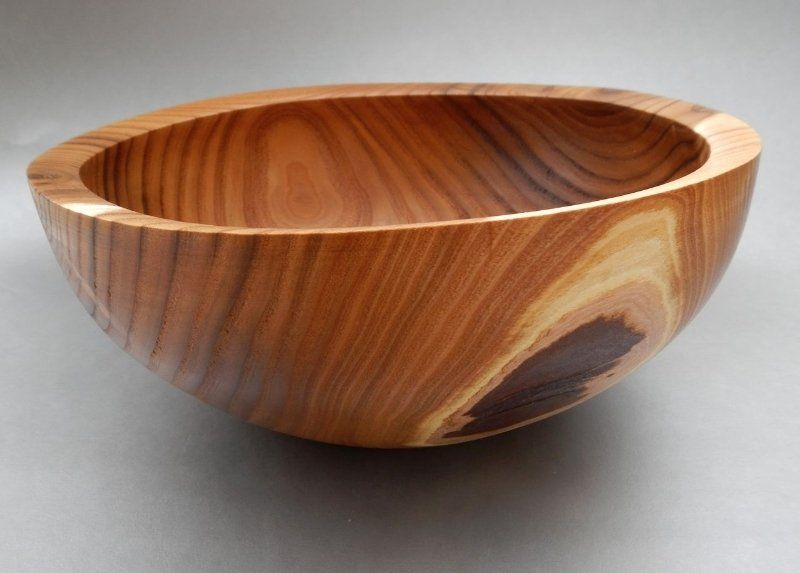 A wooden bowl is sitting on a gray surface