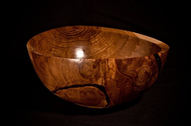 A wooden bowl is sitting on a black surface.