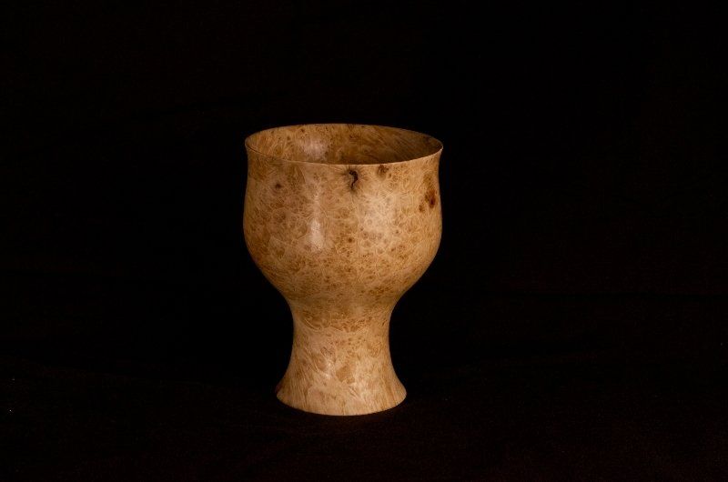 A small wooden cup is sitting on a black table.