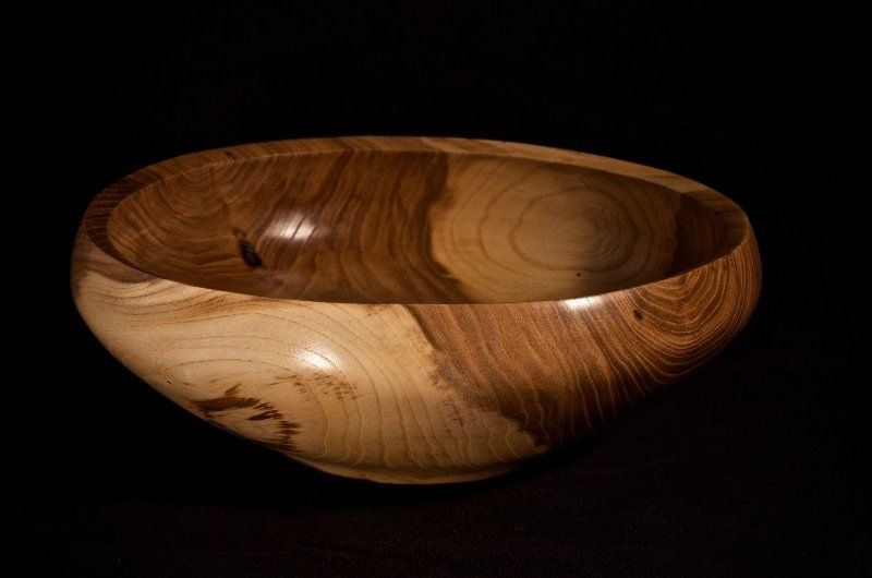 A wooden bowl is sitting on a black surface.