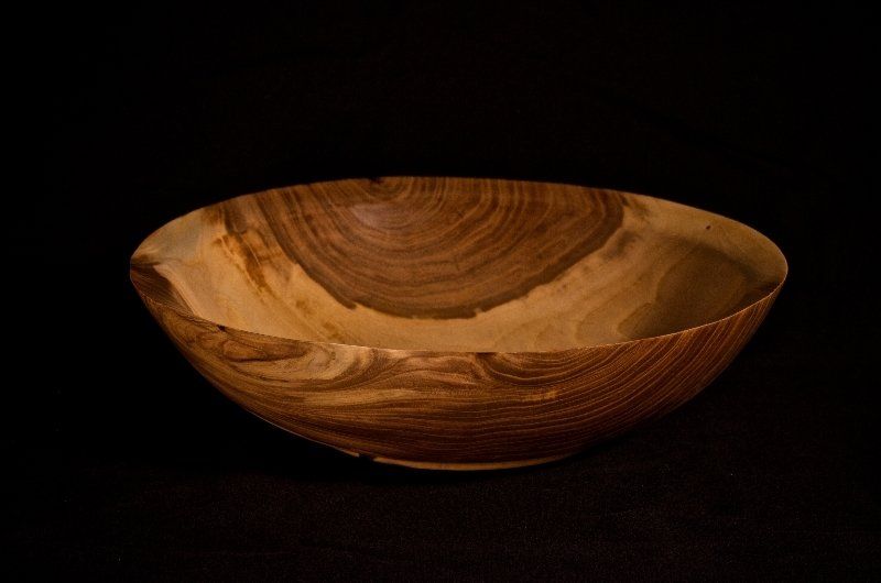 A wooden bowl is sitting on a black surface.
