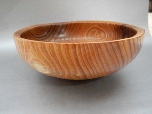 A wooden bowl is sitting on a gray surface.
