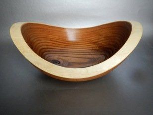 A wooden bowl with a curved edge is sitting on a table.