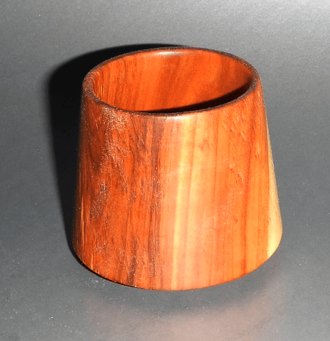 A wooden cone shaped object is sitting on a black surface