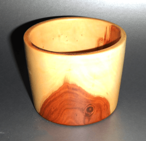 A small wooden cup with a shadow on the table