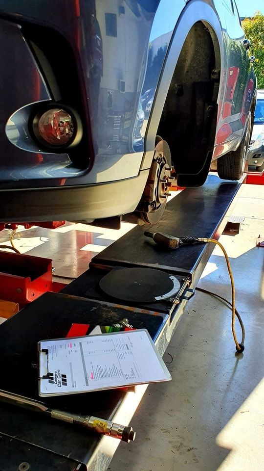 A Car Is Sitting On A Lift In A Garage — Camden Haven Tyre & Brake Centre In Laurieton, NSW