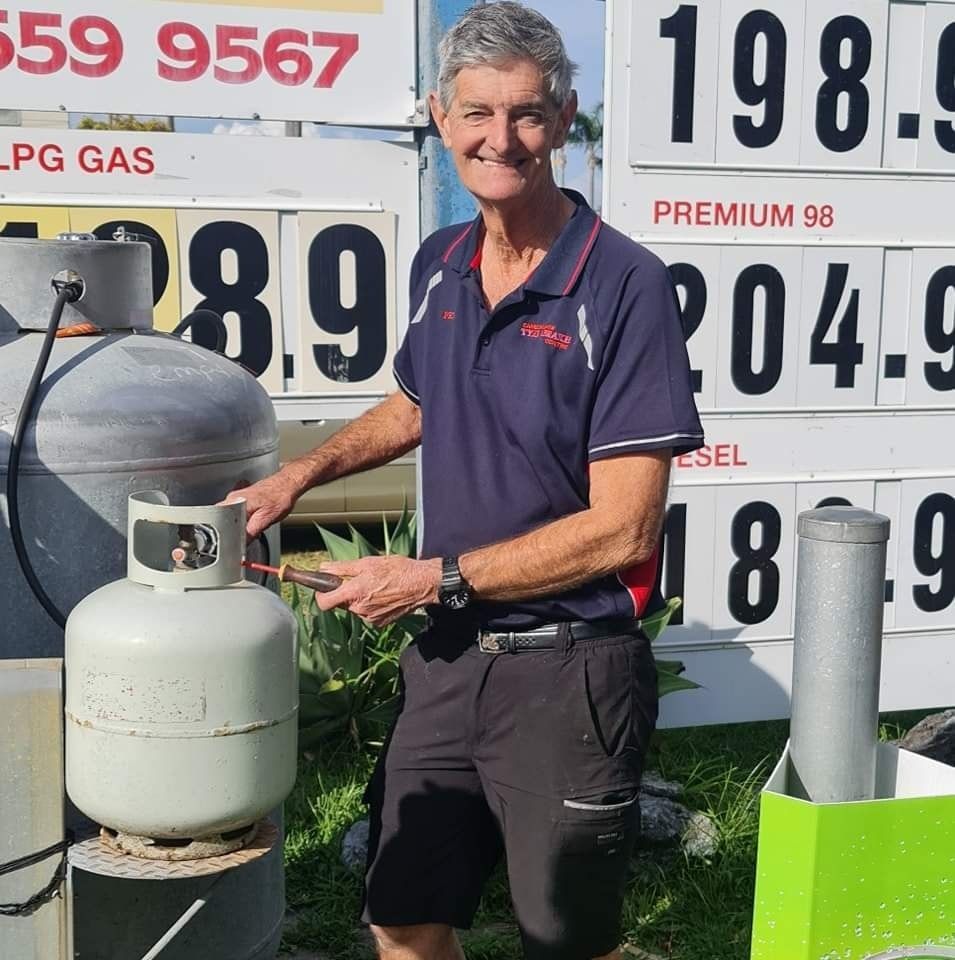 A Man Is Standing In Front Of A Sign That Says LPG Gas — Camden Haven Tyre & Brake Centre In Laurieton, NSW