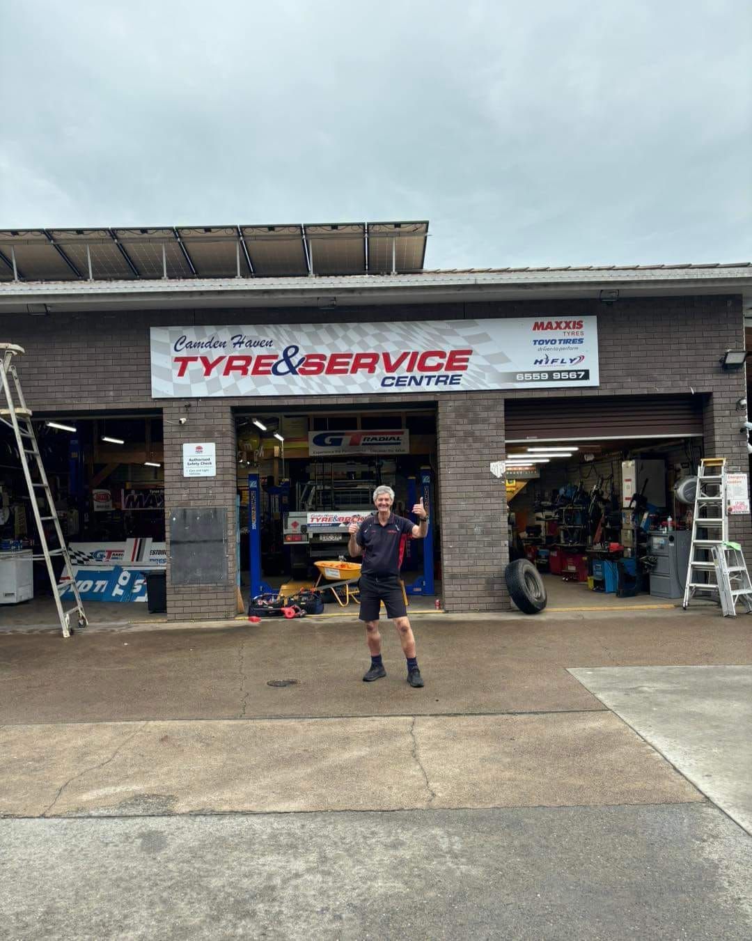 A Man Is Standing In Front Of A Tire And Service Center — Camden Haven Tyre & Brake Centre In Laurieton, NSW