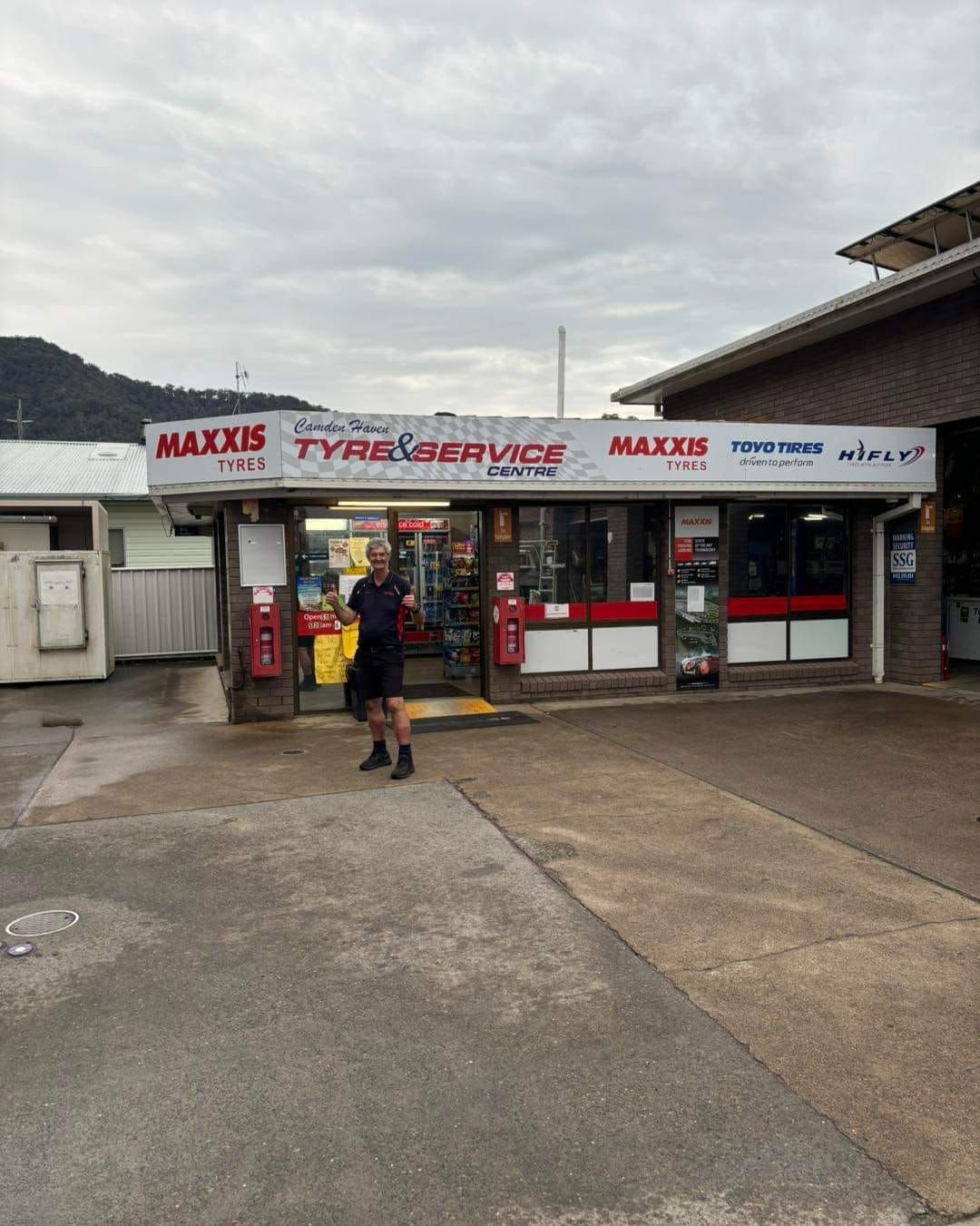 A Man Is Standing In Front Of A Tire Shop — Camden Haven Tyre & Brake Centre In Laurieton, NSW