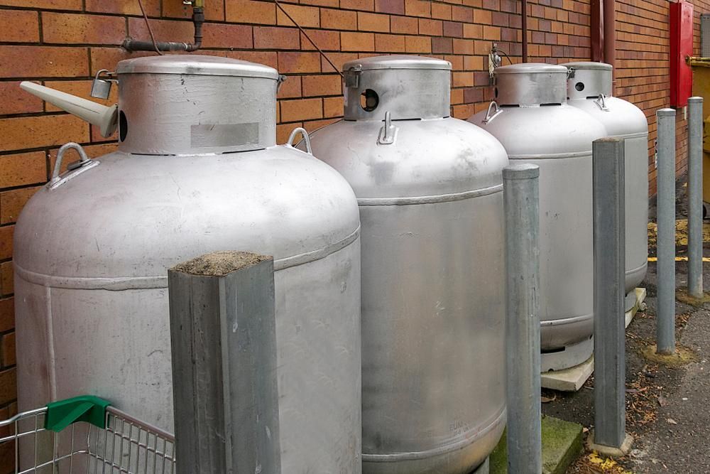A Row Of Gas Tanks Are Lined Up In Front Of A Brick Wall — Camden Haven Tyre & Brake Centre In Laurieton, NSW