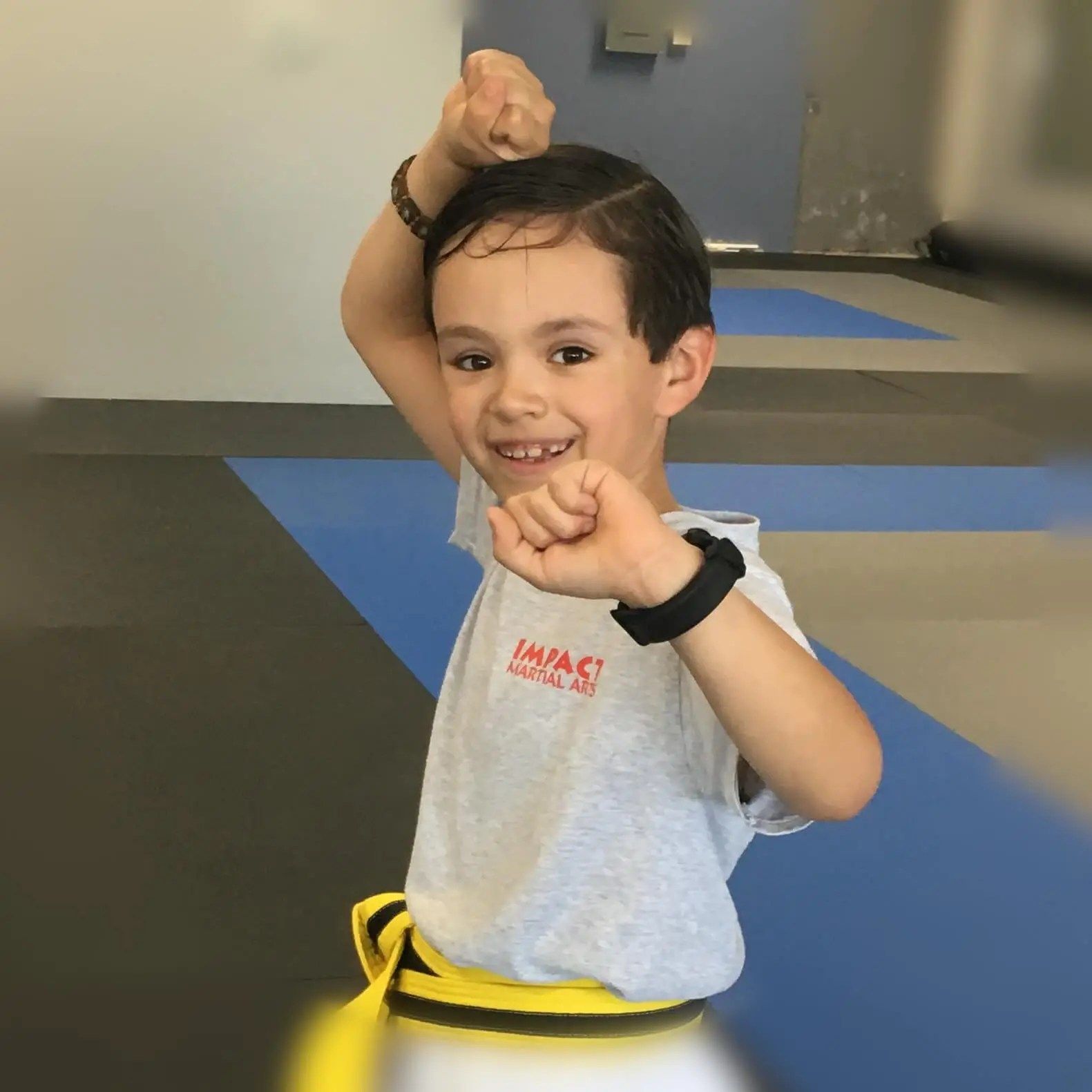 Eight-year-old boy demonstrating martial arts stance with confidence, wearing yellow belt at Impact 