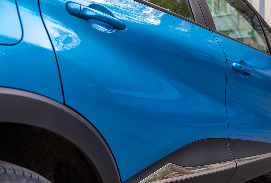 A close up of a blue car parked in a parking lot.