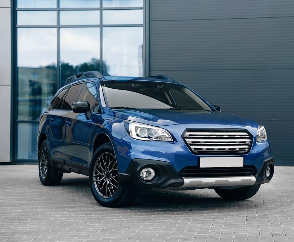 A blue suv is parked in front of a building.