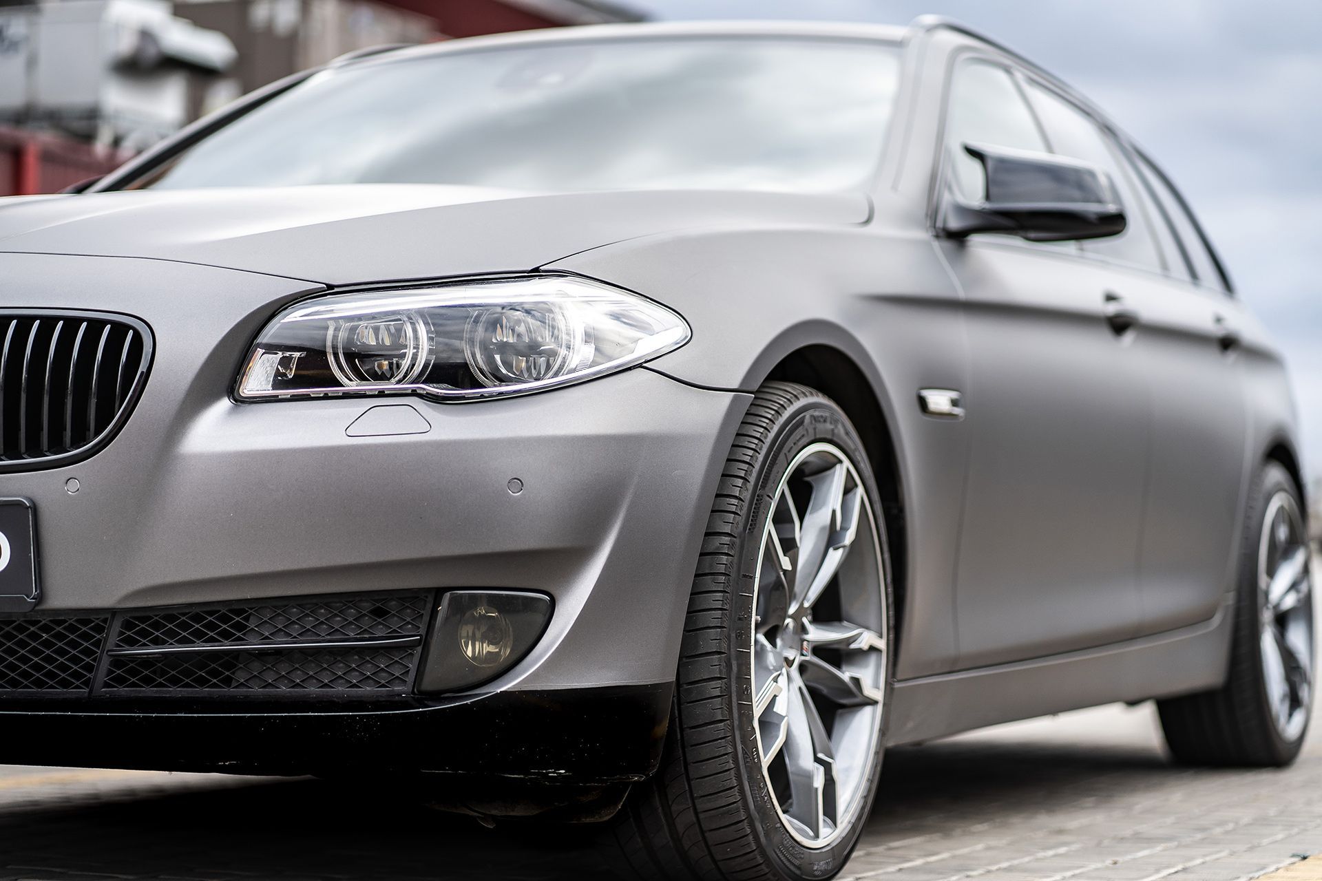 A gray bmw 5 series is parked on the side of the road.
