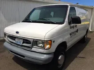 White Ford van with company logo parked outside a building.