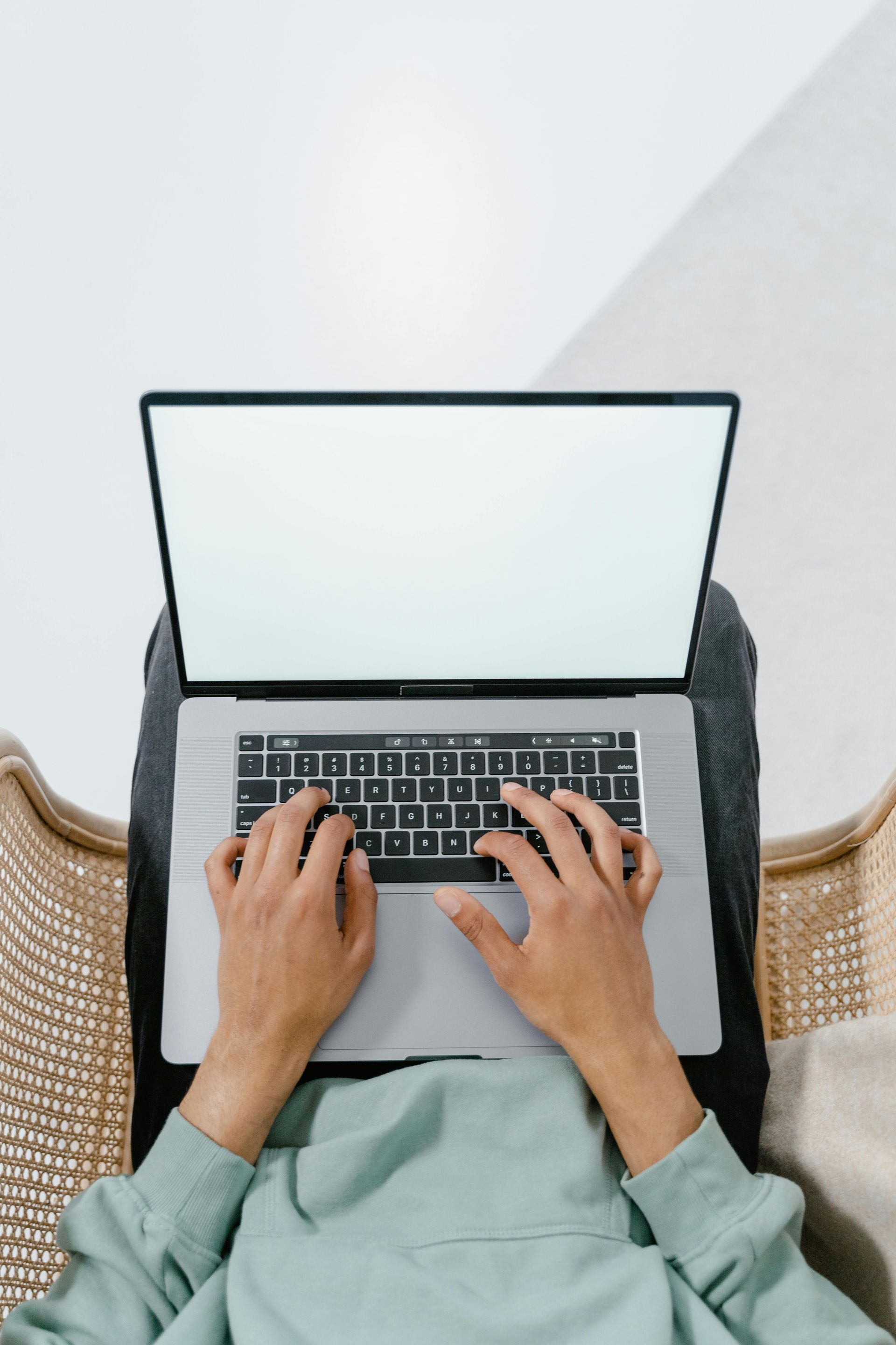 woman typing on a laptop keyboard that is on her lap.