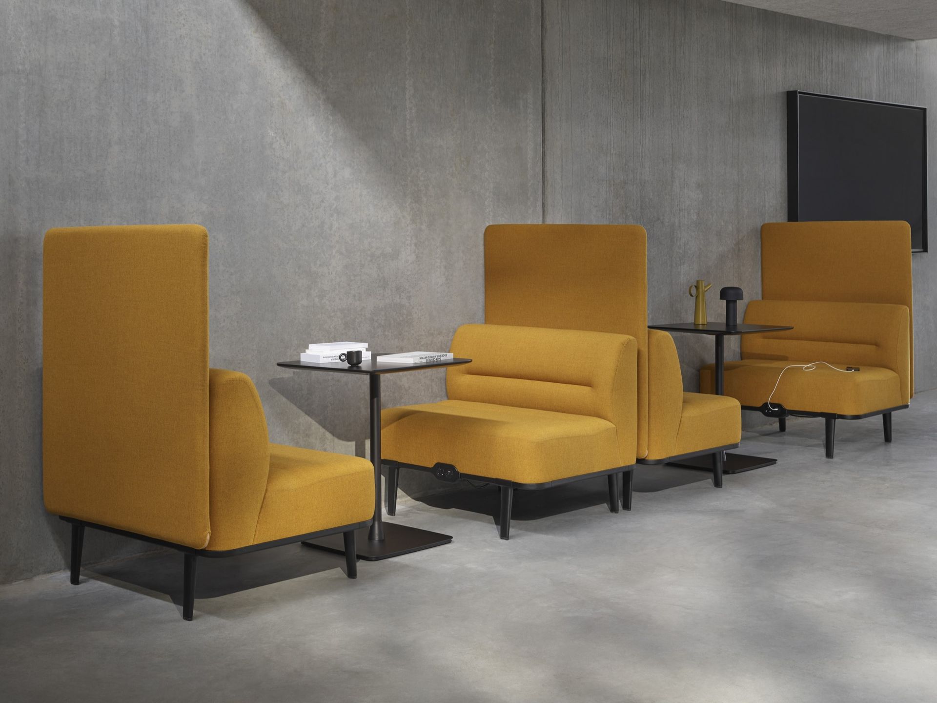 A row of yellow lounge chairs with privacy dividers, each pair facing each other with small black meeting table between.