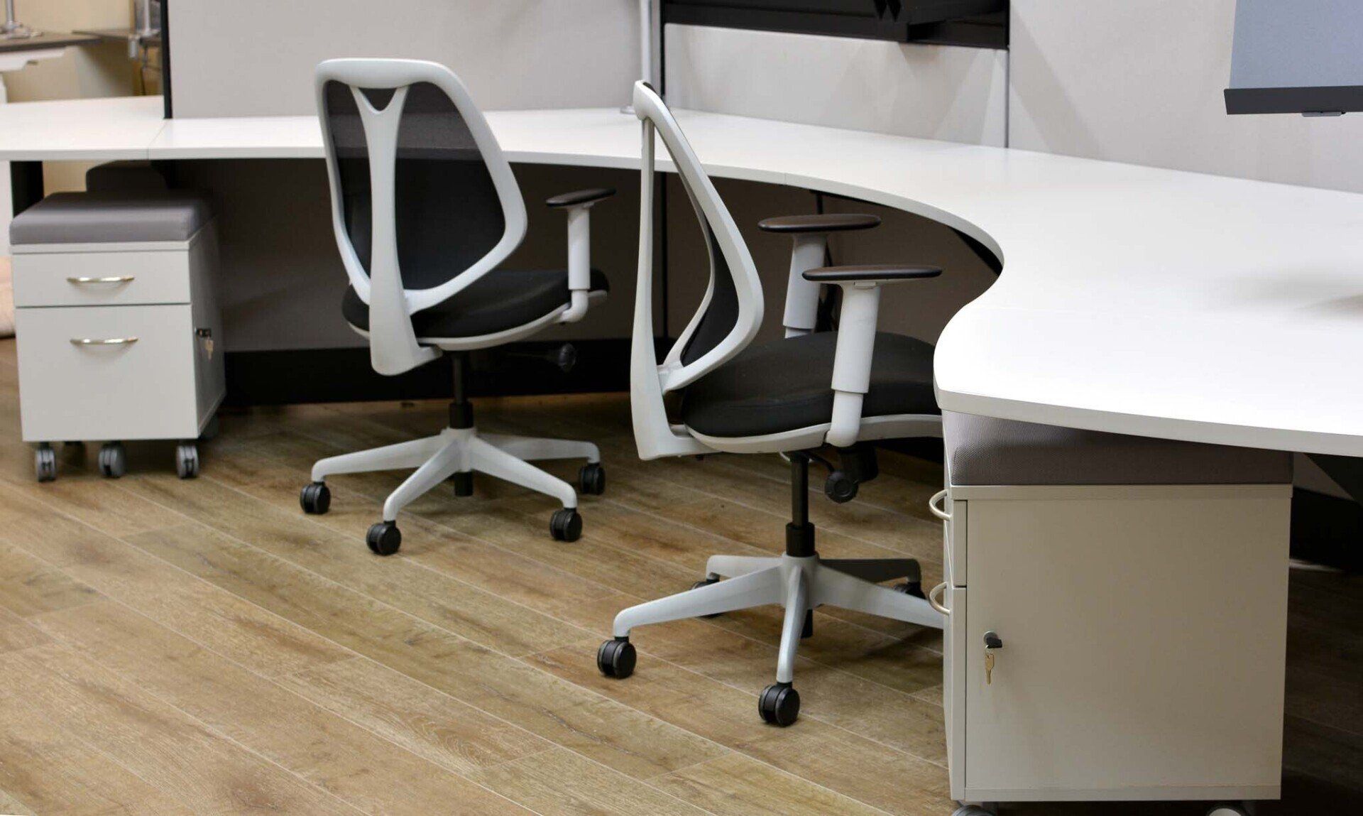 a cubicle with two chairs and a white desk