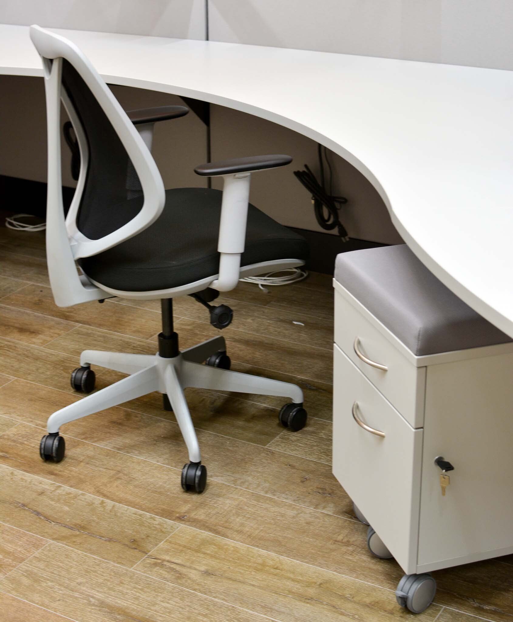 a black and white office chair sits in front of a curved desk