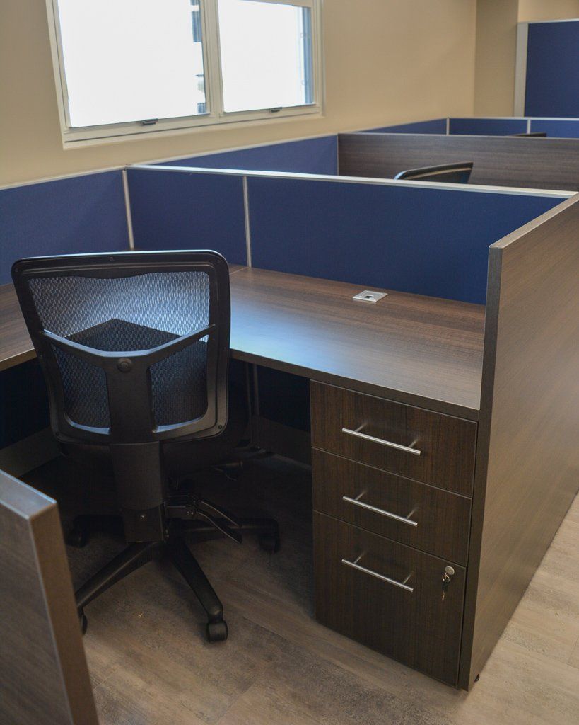 a cubicle in an office with a chair and drawers