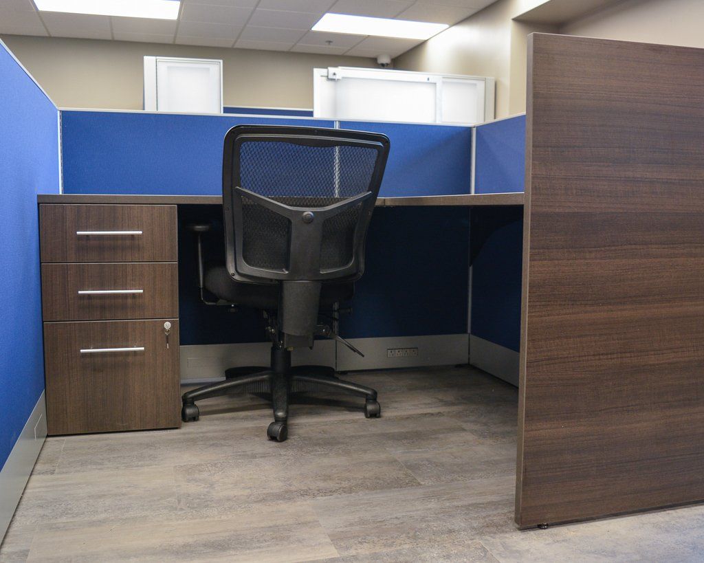 an office cubicle with a chair and drawers