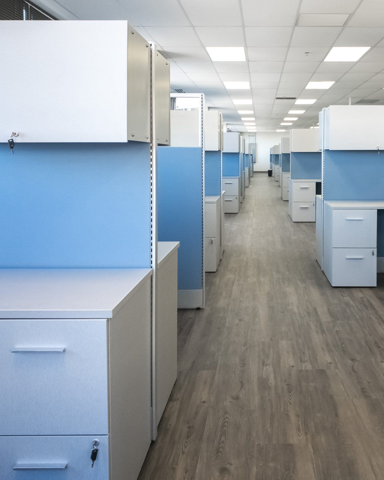 a row of cubicles with blue walls and white cabinets