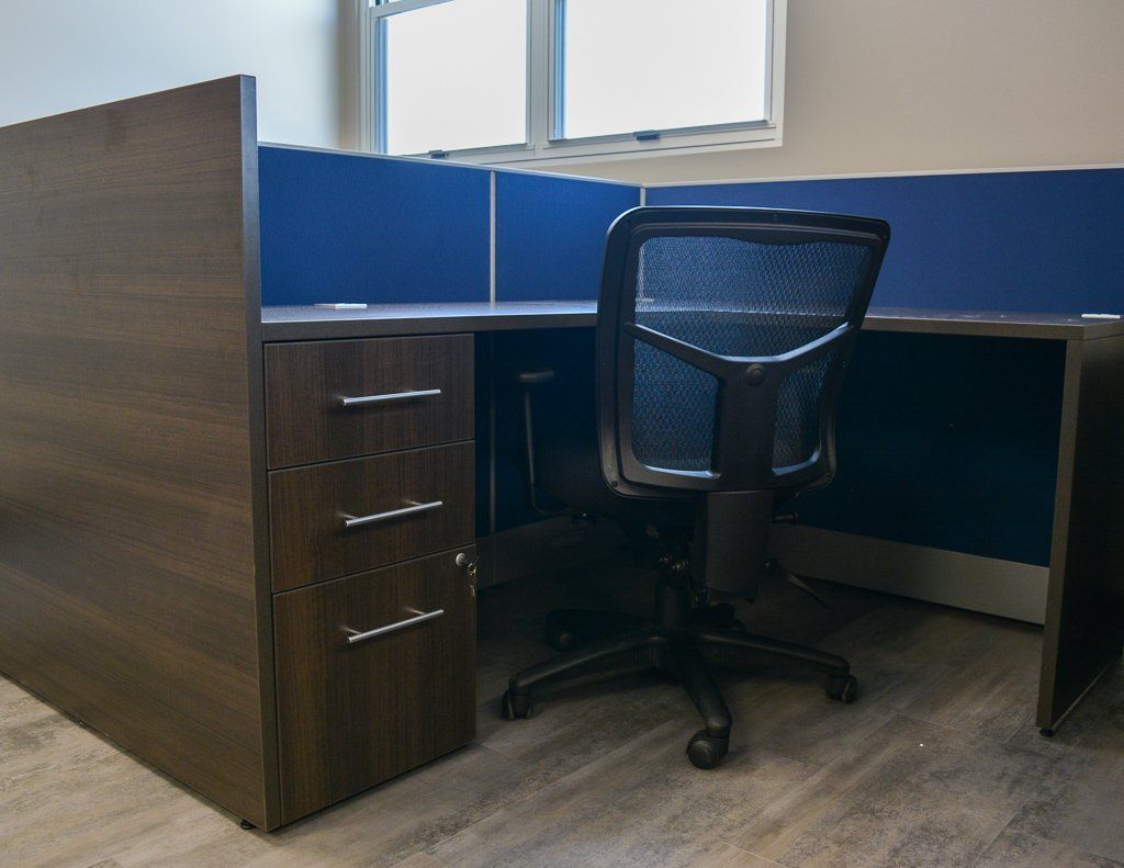 a black office chair sits at a desk in a cubicle