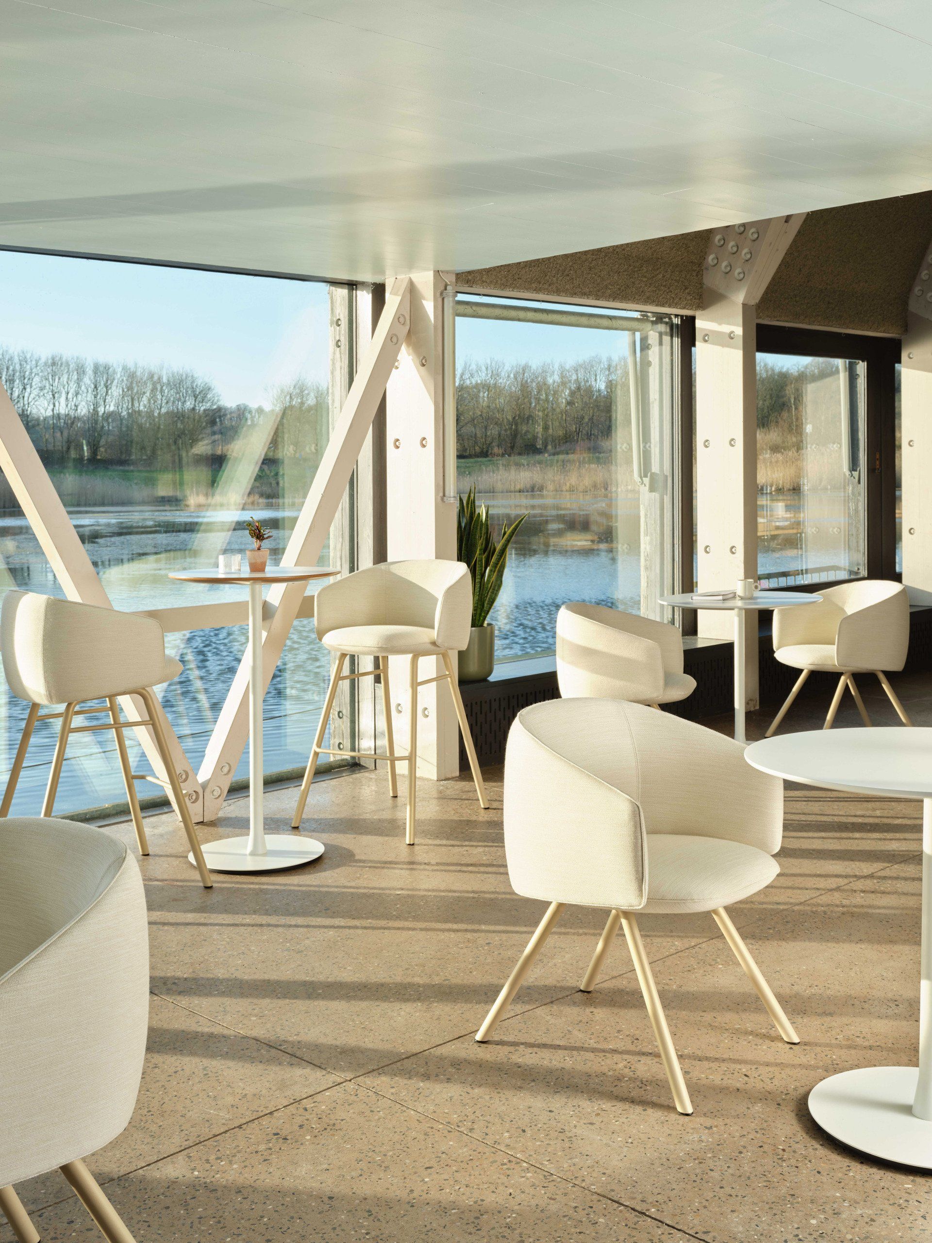 white tables and chairs in a room with a view of a lake