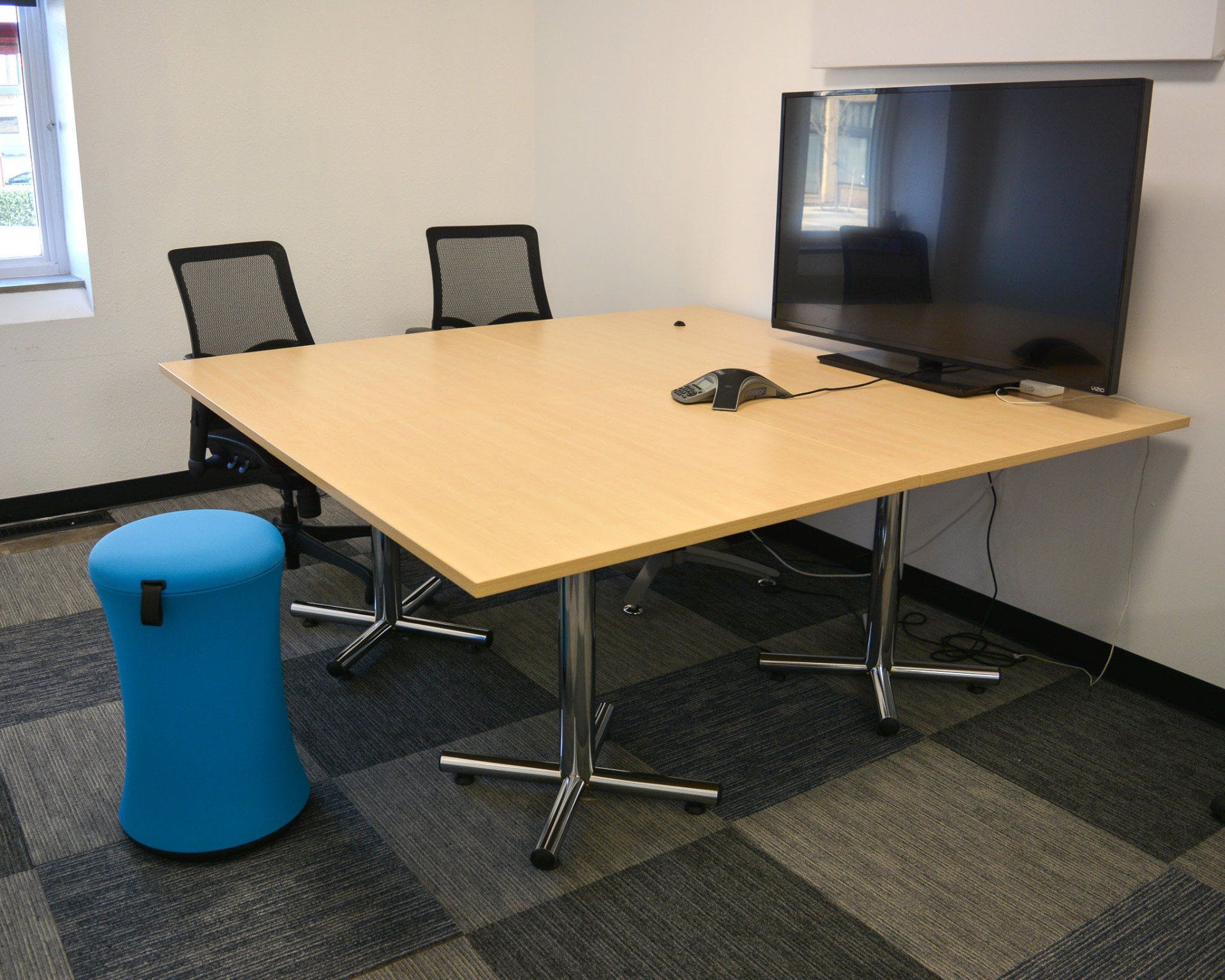 a meeting room with two tables and a flat screen tv