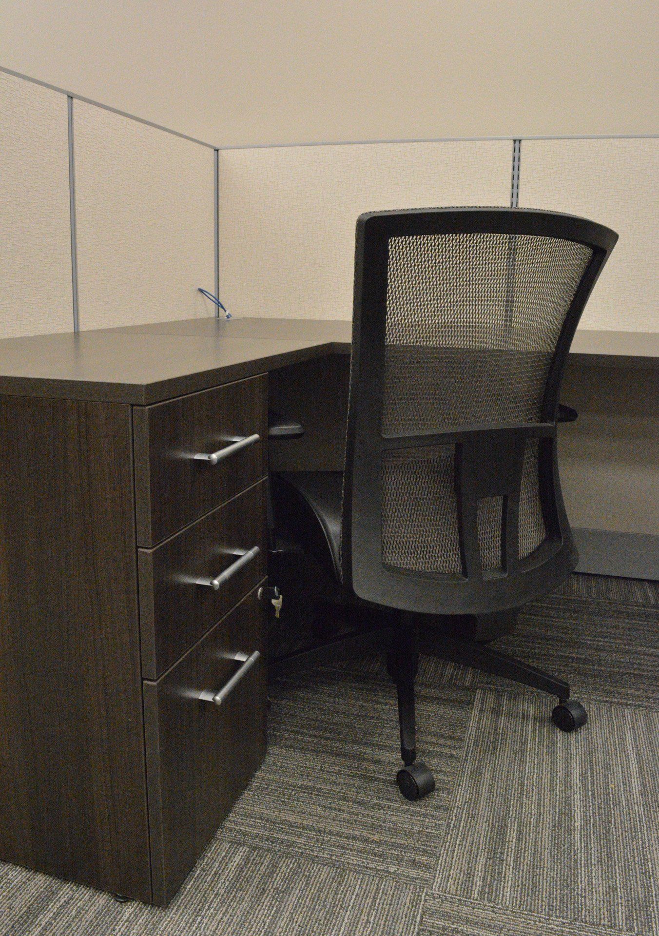 a cubicle with a desk and chair in it