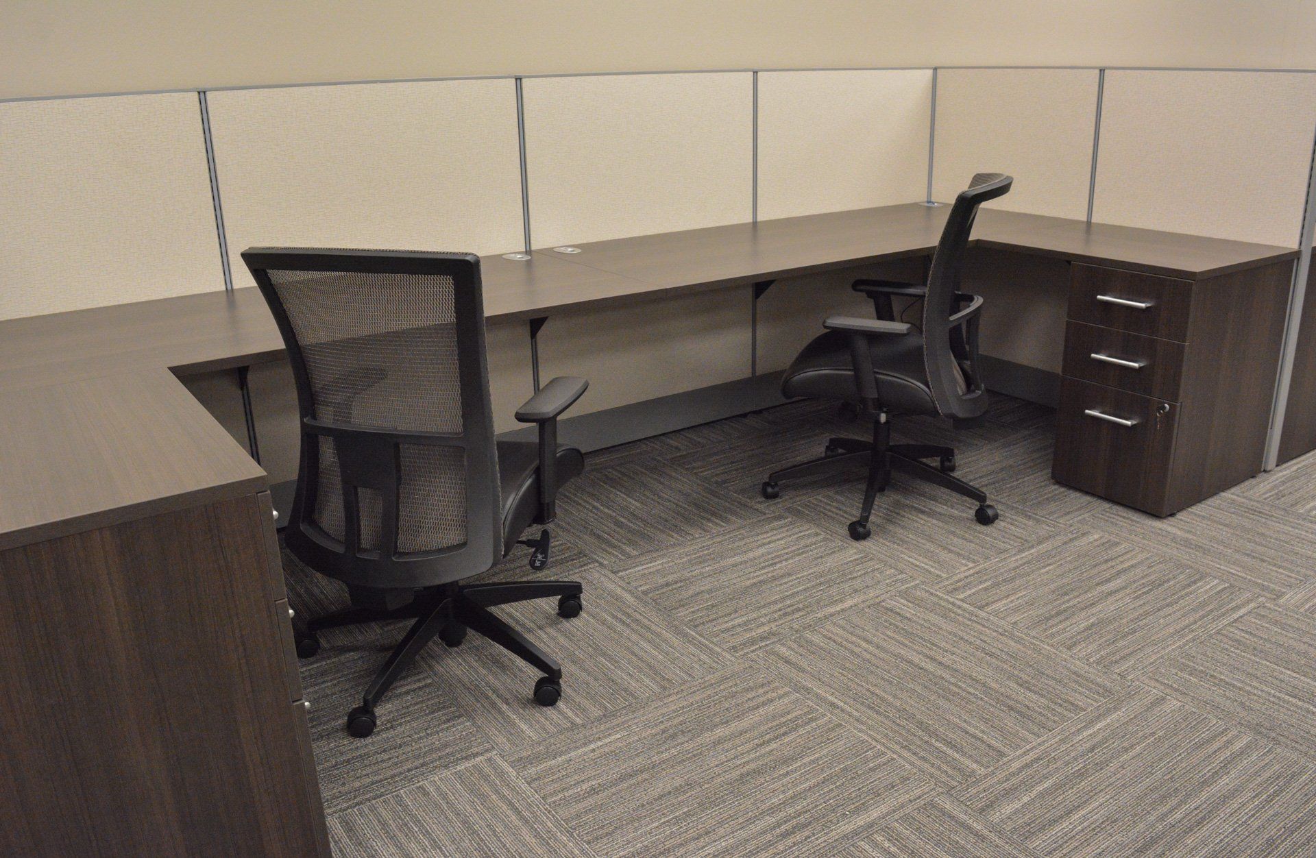 a cubicle with two chairs and side-by-side desks