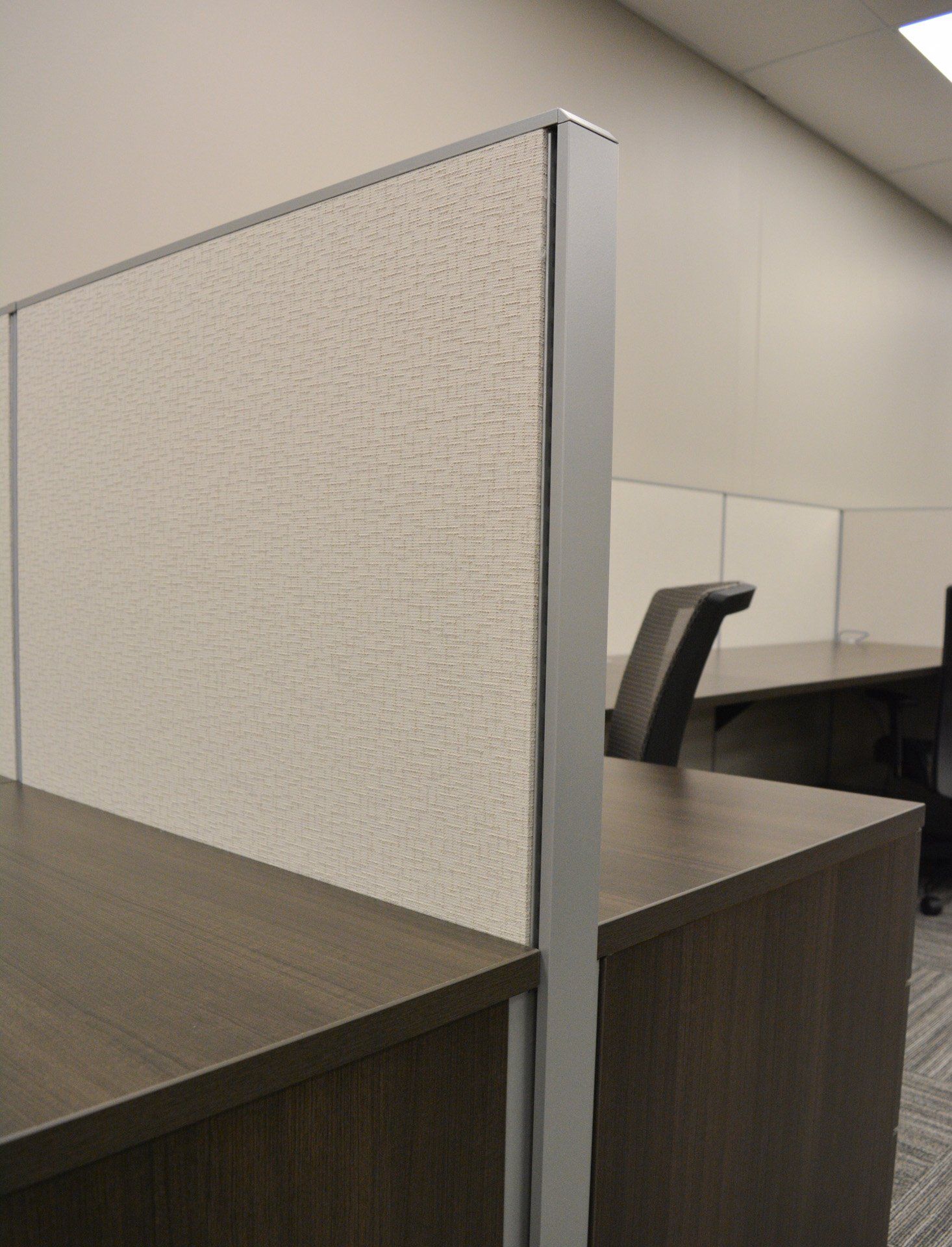 a cubicle with a tan divider between two desks