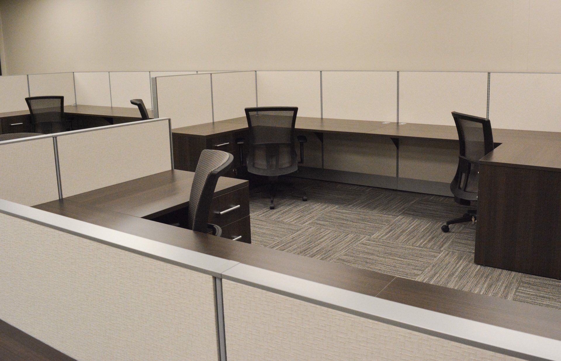 an office cubicle with three desks and three chairs