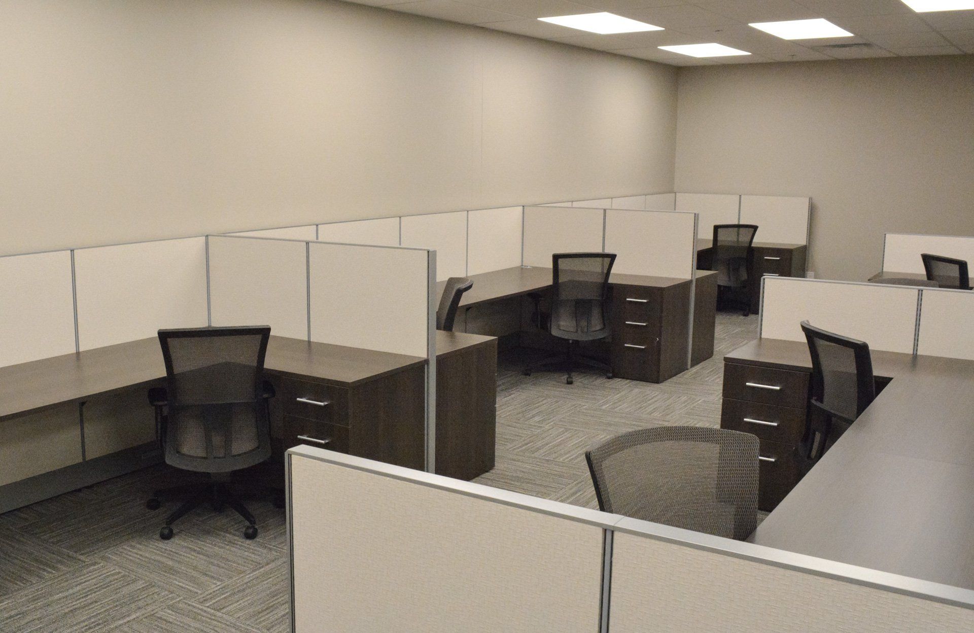 cubicles in an office with black chairs and desks