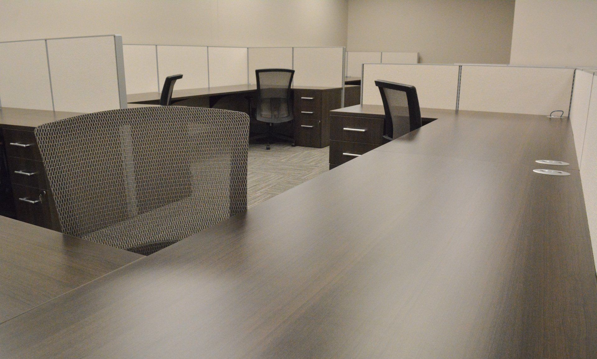 a cubicle with two chairs and side-by-side desks
