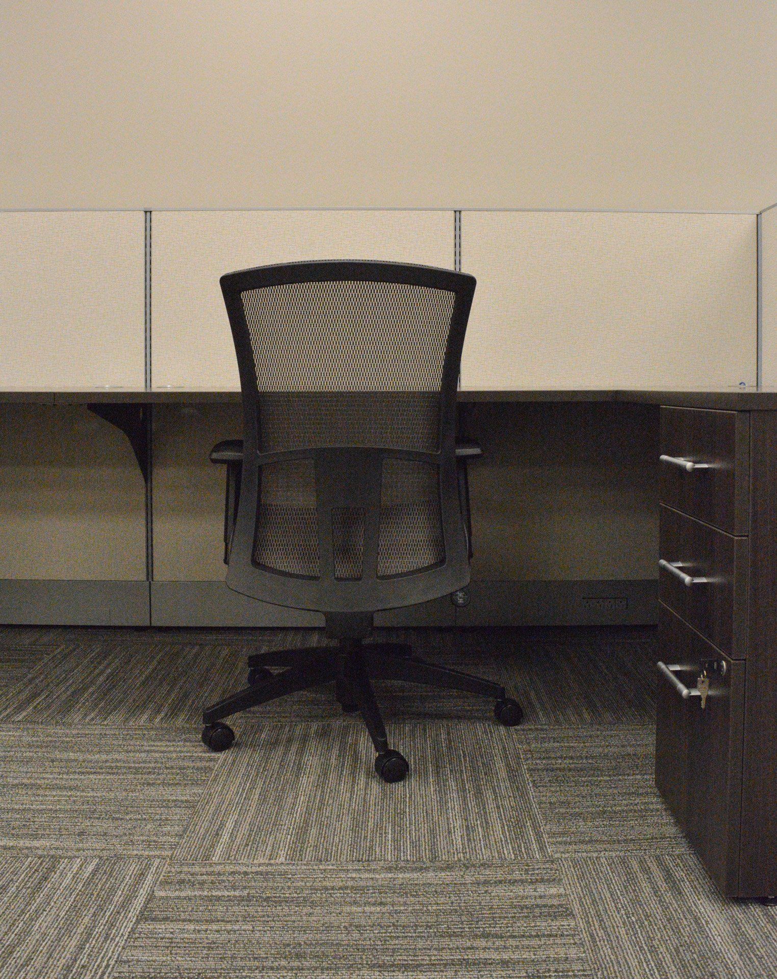 a black office chair sits in front of a desk