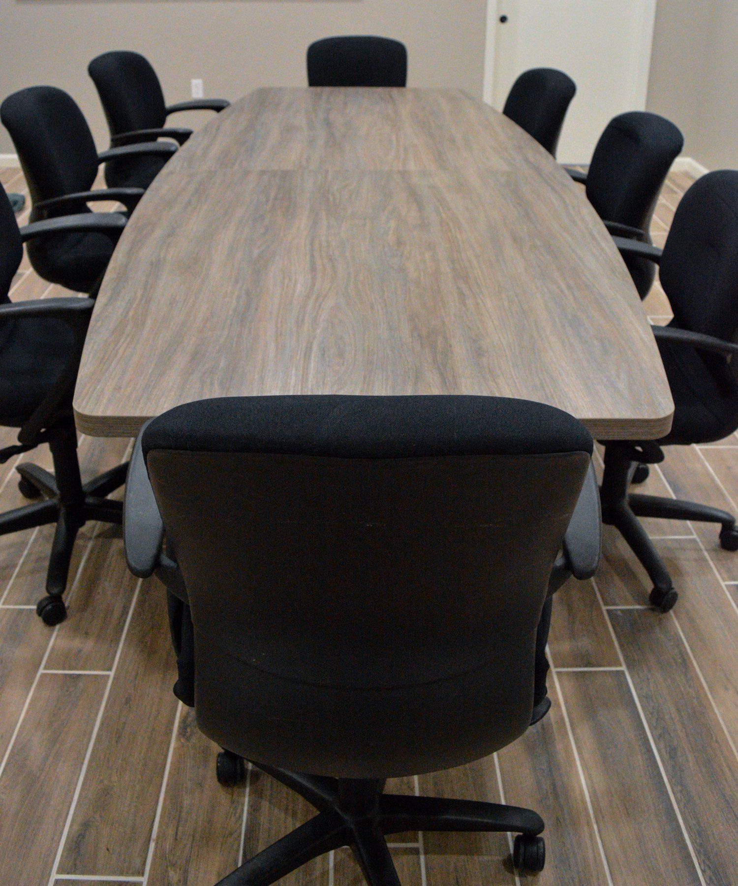 a long wooden conference table with black chairs around it