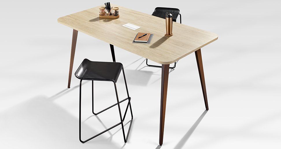 a wooden desk with a black stool next to it
