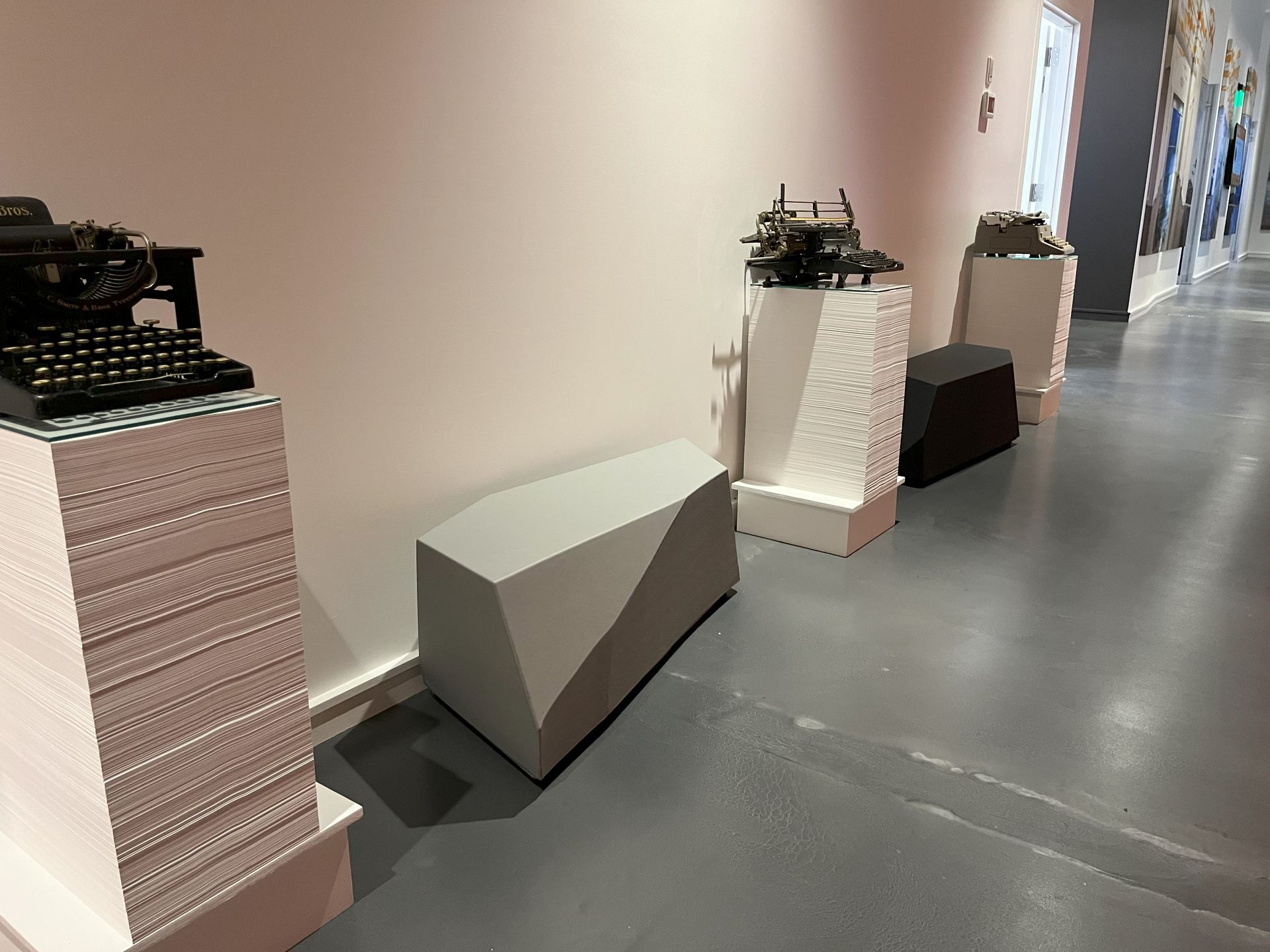 Geometric benches in a hallway with pedestal displays. 