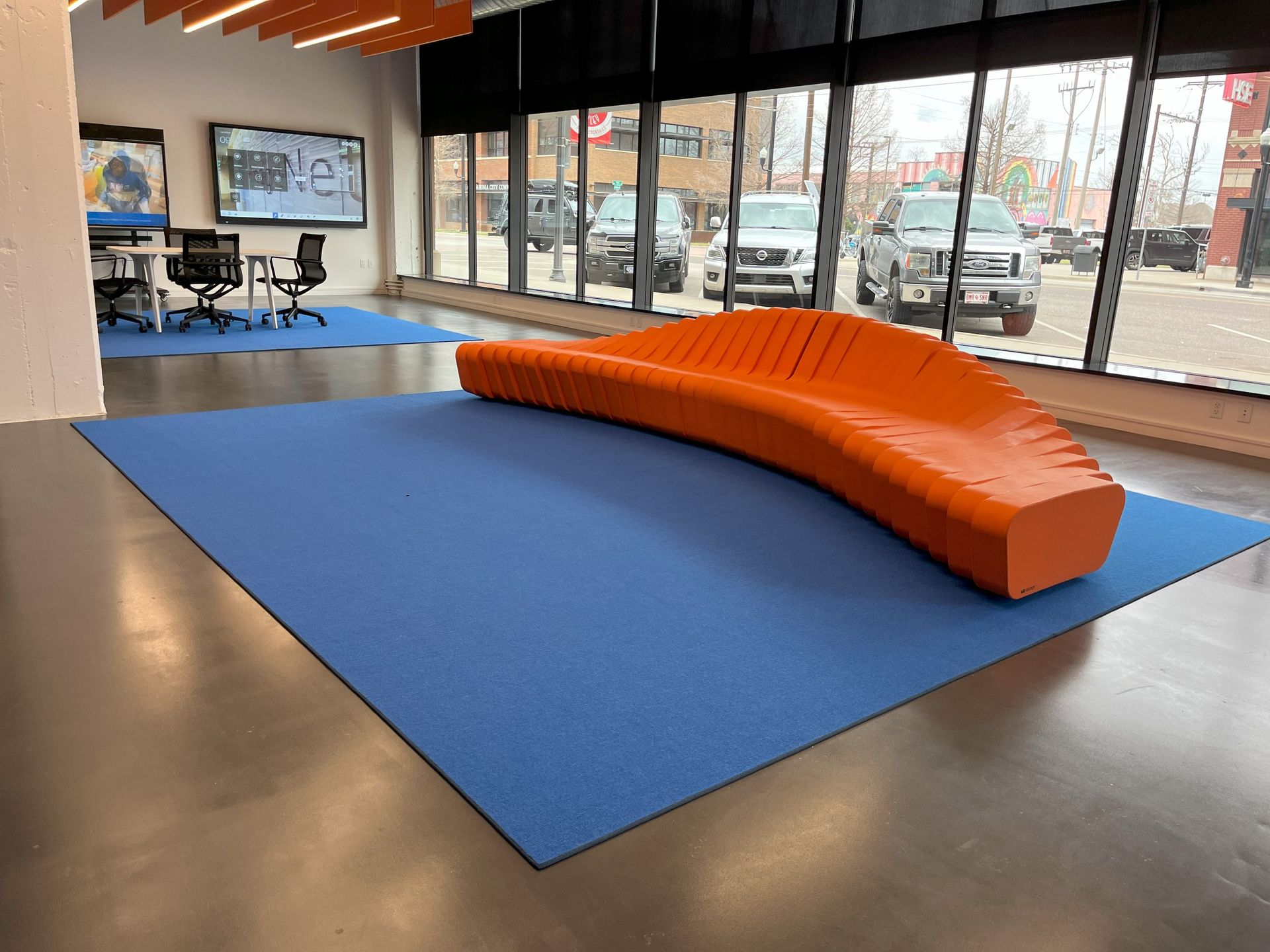 A modular orange couch is sitting on a blue rug in a room.