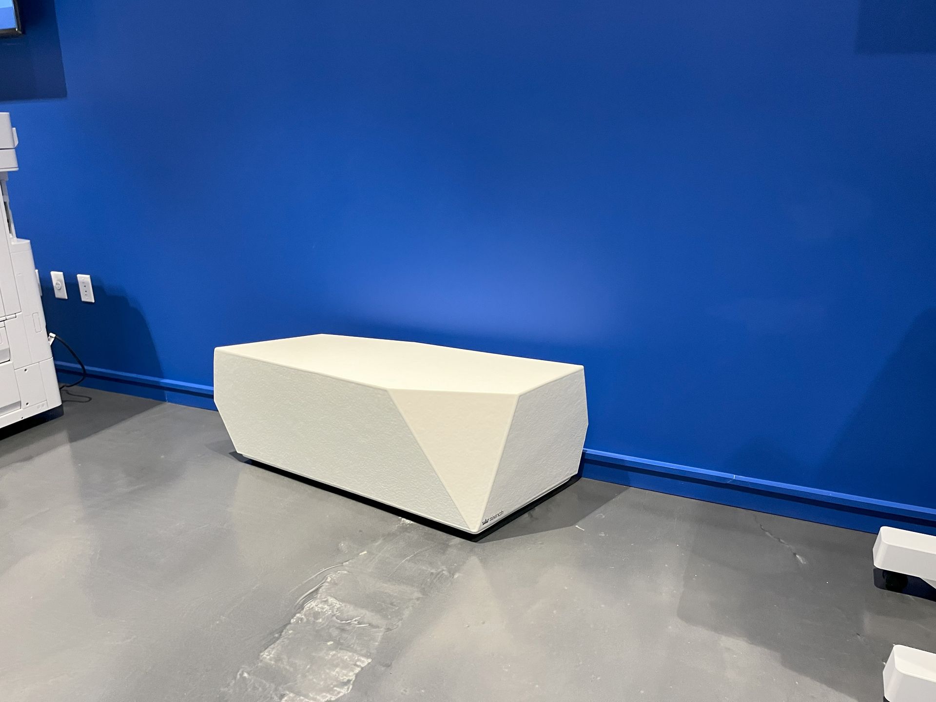 White Rock Elements FlexPlus bench against blue wall and concrete floor.