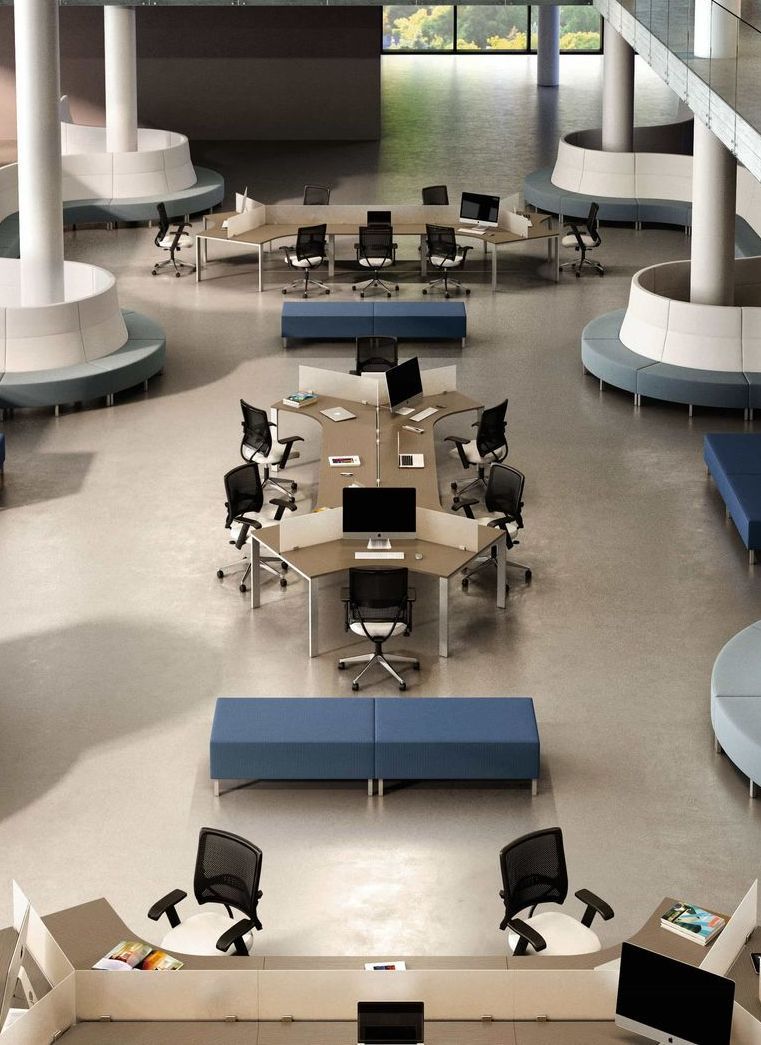 overhead view of an open office space with modular workstation groups in the middle, surrounded by blue ottomans and curved sectional sofas.