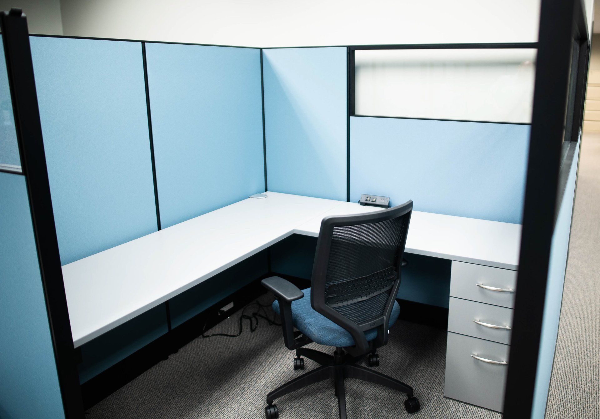 An office cubicle with a chair and a desk