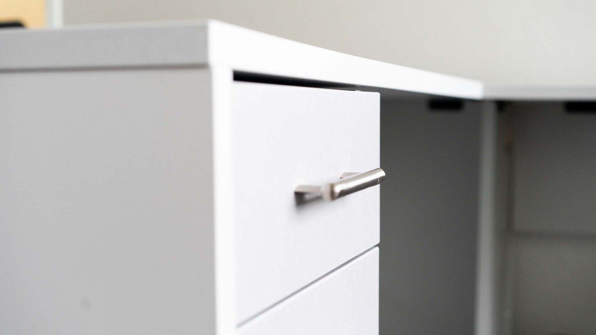 a close up of a white drawer with a silver handle