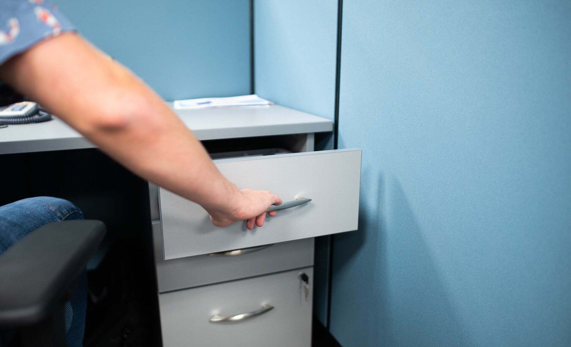 a person is opening a drawer in a cubicle