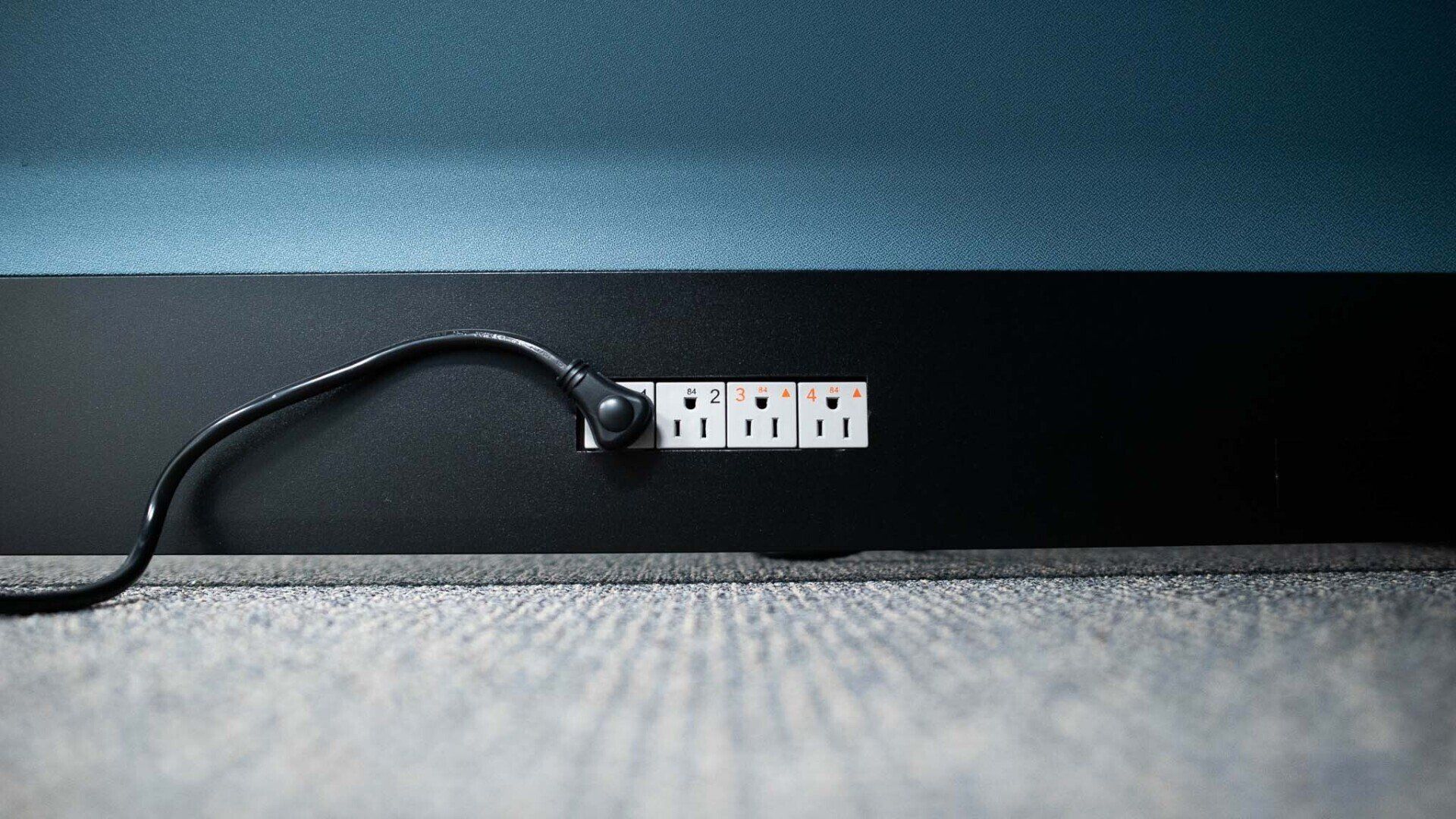 a power cord is plugged into a row of sockets on a cubicle panel